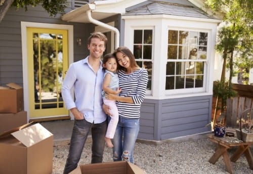 family with young child in their arms moving into a new house