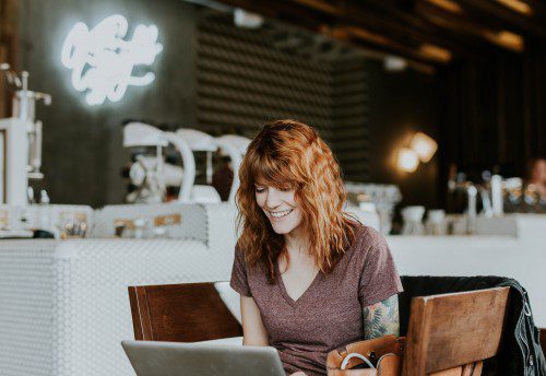 Female accountant working wage subsidy on laptop in cafe