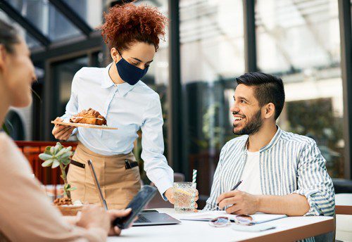 accountant in a working meeting at a cafe by waitress with mask on