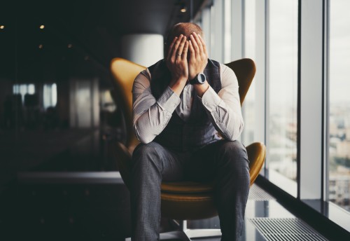 Frustrated businessman on armchair near window