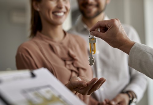 Close-up of couple receiving new house keys from real estate agent.