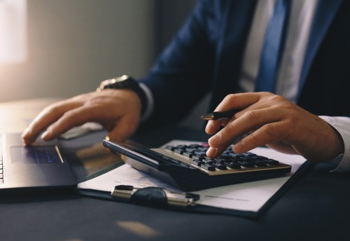 Businessman with pen in hand, finger hovering over a laptop