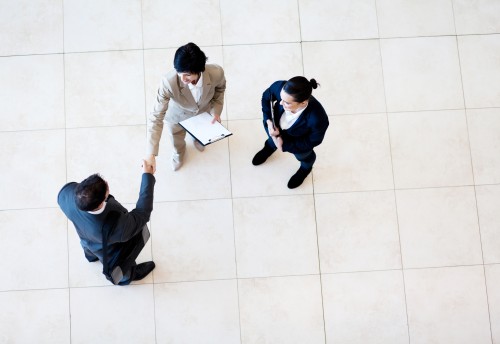 group of 3 people in suits shaking hands