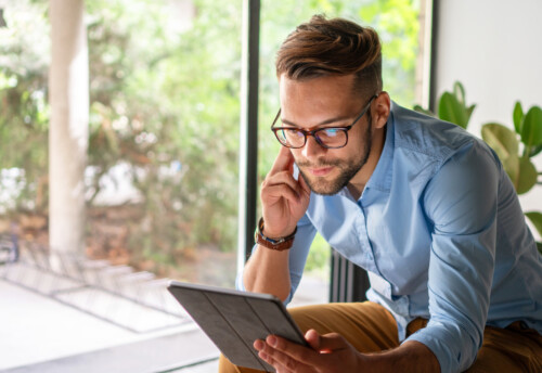 Young man smiling looking at digital tablet