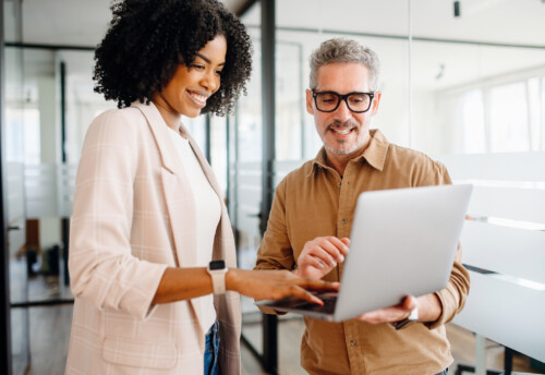Black businesswoman and her senior male colleague engage warmly with a laptop