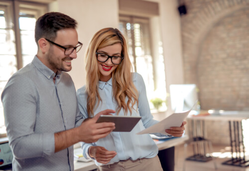 Young business woman and businessman are using tablet and document