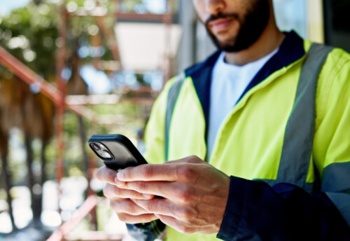 Hands, smartphone and construction site with texting, person or contact with info for building development. Engineer, phone and check with network, architecture and reading on mobile app at property