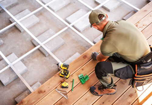 Construction Worker Installing Wooden Flooring in a Residential Space During Daylight Hours With Tools Nearby