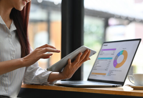 Close up of Businesswoman analyzing income charts and graphs with modern laptop and tablet. Business analysis and strategy concept.